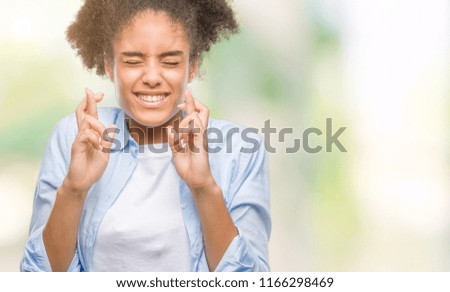 Young afro american woman over isolated background smiling crossing fingers with hope and eyes closed. Luck and superstitious concept.