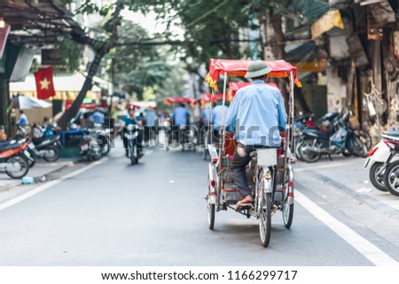 Traditional cyclo ride down the streets of Hanoi, Vietnam. The cyclo is a three-wheel bicycle taxi that appeared in Vietnam during the French colonial period. Royalty-Free Stock Photo #1166299717