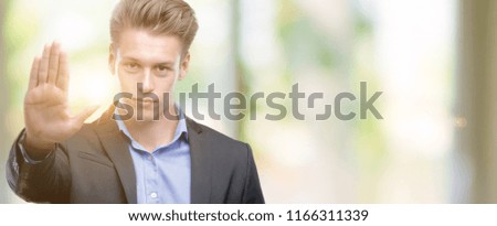 Young handsome blond business man with open hand doing stop sign with serious and confident expression, defense gesture