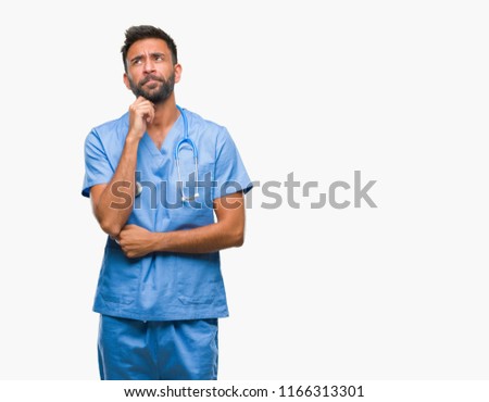 Adult hispanic doctor or surgeon man over isolated background with hand on chin thinking about question, pensive expression. Smiling with thoughtful face. Doubt concept.