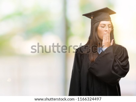 Young hispanic woman wearing graduated cap and uniform bored yawning tired covering mouth with hand. Restless and sleepiness.