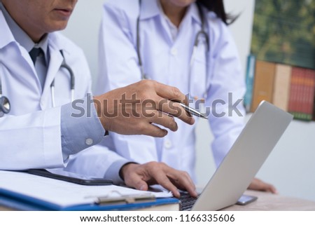 Medical teamwork concept. Two doctors having discussion about patient diagnosis, case study on laptop computer with smart phone and book on desk in hospital. Royalty-Free Stock Photo #1166335606