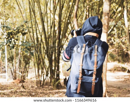 photographer and adventure in nature concept from beauty long hair asian woman in warm suit and backpack survey and take picture in tropical forest