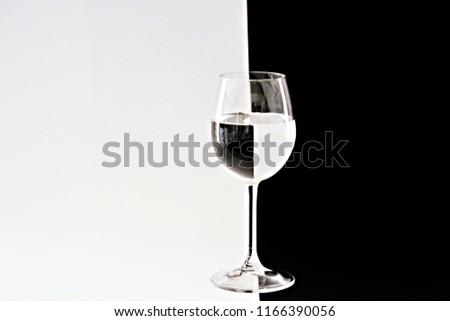 The water contained in a wine glass breaks the black and white background in exactly the opposite direction - art to clarify light reflection through round bodies - concept in black and white