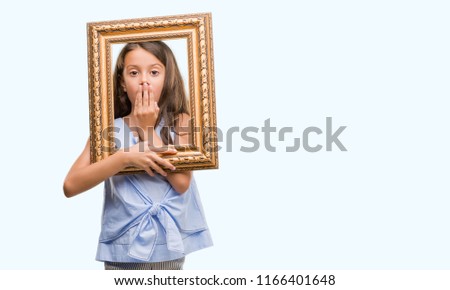 Brunette hispanic girl holding vintage art frame cover mouth with hand shocked with shame for mistake, expression of fear, scared in silence, secret concept