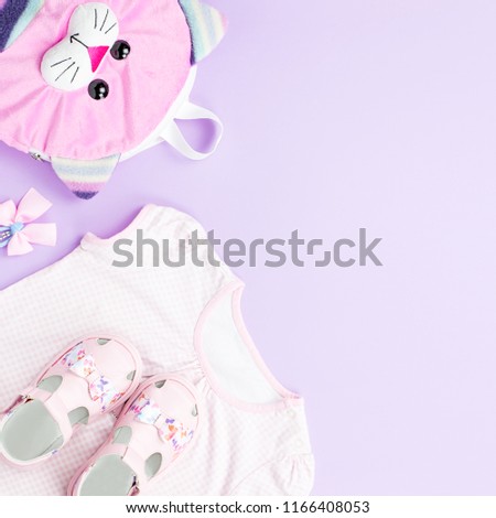 Little girl clothes collection flat lay with t-shirt, jeans, sandals, backpack on pastel background.