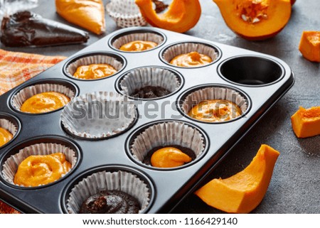 close-up of uncooked pumpkin chocolate muffins for halloween party. ingredients on a concrete table, view from above