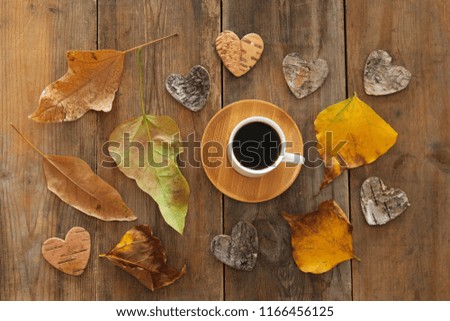 top view image of coffee cup over wooden table and dry autumn leaves