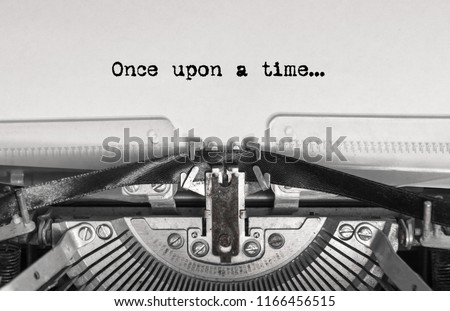 once upon a time... the text is typed on a vintage typewriter with black ink on old paper, close-up Royalty-Free Stock Photo #1166456515