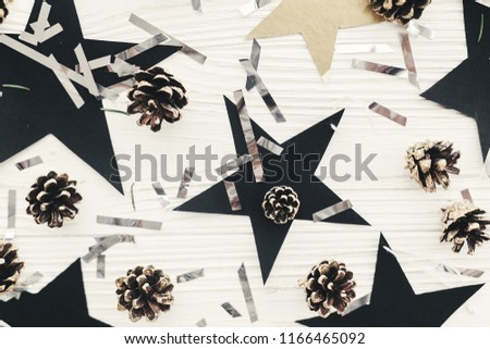 modern christmas image with golden pine cones, silver confetti, black stars on white wood. holiday greeting card. stylish winter flat lay. Merry Christmas