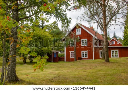 A typical red and white Scandinavian house for a family on the countryside in Sweden with a lot of garden around it Royalty-Free Stock Photo #1166494441