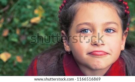 Cute adorable toddler girl portrait with autumn leaves on the ground at the background. Child outdoor in park or forest.