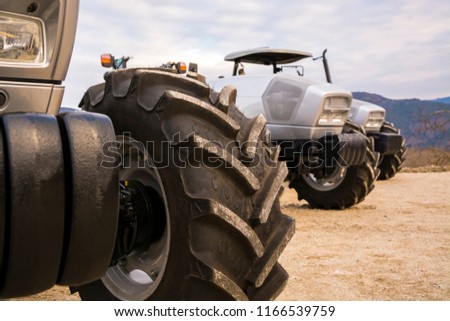 Photo of a new tractor ready to work early in the morning as the sky has a surreal light. Front tires of three gray tractors parked side by side on a cloudy day in Vinhais region of Tras-o