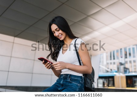 Portrait of cheerful Indian woman with beautiful face and smile using mobile phone for online shopping with discount sales. Successful asian blogger blog post into social networks, walking on street.  Royalty-Free Stock Photo #1166611060