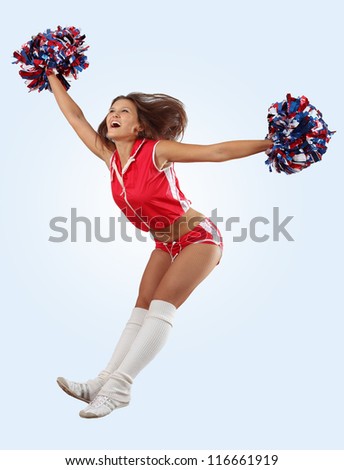Uniformed cheerleader jumps high in the air isolated on white.