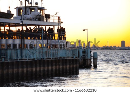Passengers wait on a departing ferry at sunset. 