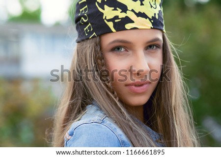Happy hipster teenager. Closeup Portrait Cute teenage girl Young Woman in Casual Clothing looking at you camera thoughtful pensive with blondish long hair green eyes with braid and bandana outdoors.