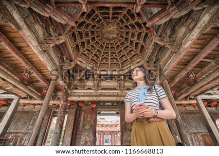 asian woman standing in the old beautiful temple. holding a mobile in hands
