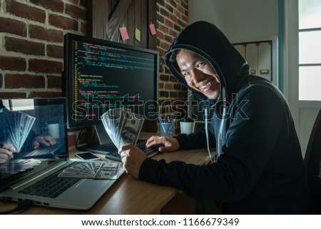 hacker looking round and holding banknote smiling with pure evilness at his working place.