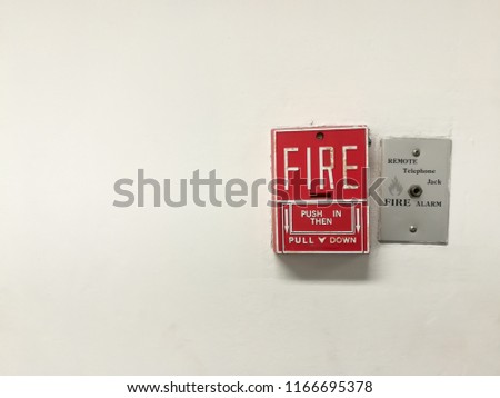 Red fire alarm switch with telephone jack connection on the white wall of building