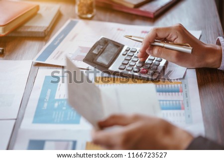Businesswoman using calculator to calculate saving account passbook and statement with financial report.Female accountant or banker use calculator. Savings, finances and economy concept. Royalty-Free Stock Photo #1166723527