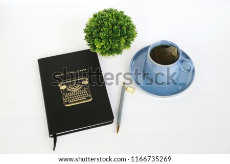 Journal and Blog with Think, Write, Create in Gold on Black Notebook with Blue Tea Cup and Green Pant on White Desk from Top View 