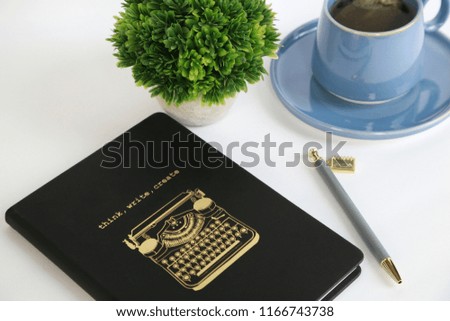 Angle View and Close Up of Journal for Blog with Words Think, Write, Create and Typewriter in Gold Lettering with Blue Teacup and Saucer and Green Plant for Business and Education and Motivation