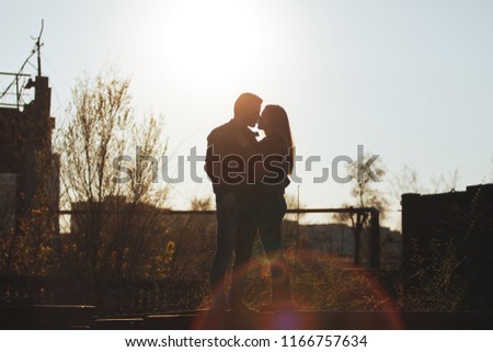 Man and woman hugging in the background of the setting sun. Silhouette. Horizontally framed shot.