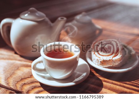 Hot black tea in a cup on a saucer with sweets. Breakfast in the sunlight.