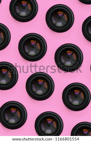 A few camera lenses with a closed aperture lie on texture background of fashion pastel pink color paper in minimal concept. Abstract trendy pattern.