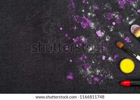 decorative cosmetics and purple loose eye shadows lying on a black background. concept of professional make up artist tools. free space for text