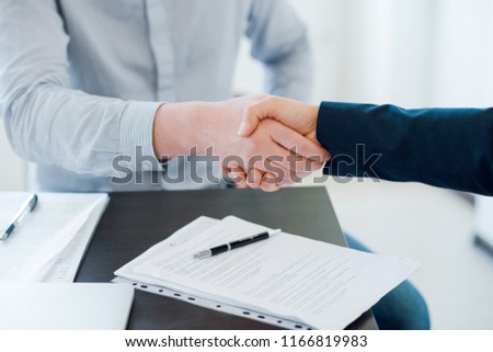 Two business man shaking hands during a meeting in the office. Documents on the table. Success deal. Dealing, greeting and partner concept. Close up