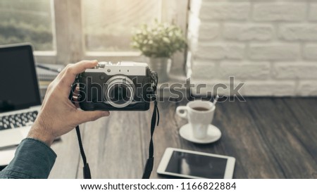 Hipster photographer at home sitting at desk and taking a selfie with his camera, point of view shot