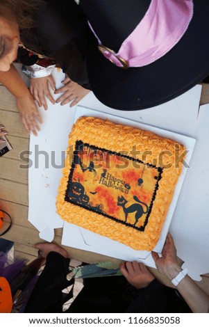 Halloween cake with black Jack o lantern and cat designed on orange colour cake like ripe pumpkin for celebration.