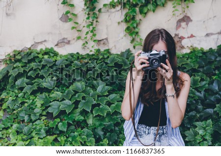 Photography and people concept - close up of young woman with vintage camera taking picture outdoors
