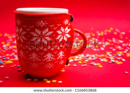 red cup with christmas pattern - white snowflakes. hot coffee. 