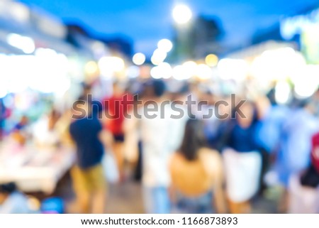 Group of blurred people shopping in outdoor market with light bokeh