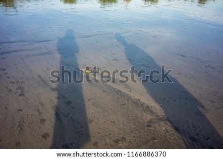people shadow on beach sand with water