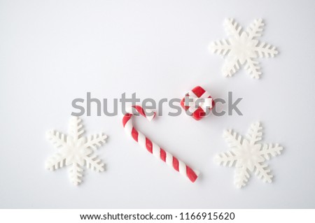 New year or christmas white background with a candy cane, a snowflake, a red box. Top view.