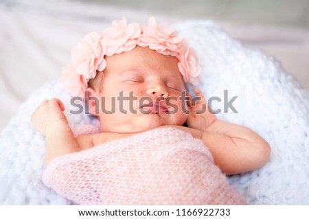 Cute Caucasian newborn infant baby girl asleep. Pink flower band on her head and pink plaid. Adorable newborn baby girl portrait studio stock image.