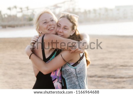 Cute pretty teen daughter with mature mother hugging in nature at sunset.