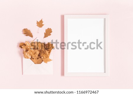 Autumn composition. Envelope with golden leaves, photo frame on pastel pink background. Autumn, fall concept. Flat lay, top view, copy space