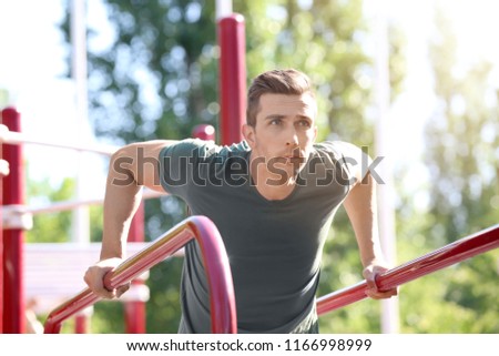 Sporty young man training on athletic field outdoors