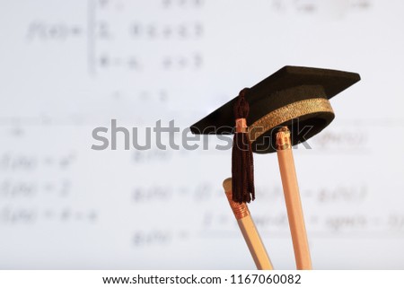 Education Graduate study concept: Graduation hat on pencils with formula arithmetic equation graph on projecter screen at university classroom. Ideas for knowledge learning success and Back to School