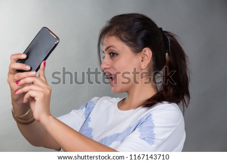 A young Indian female model clicking her selfie with her phone or mobile