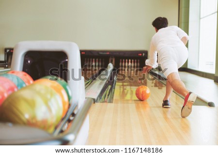 Young man playing bowling at the sport club.