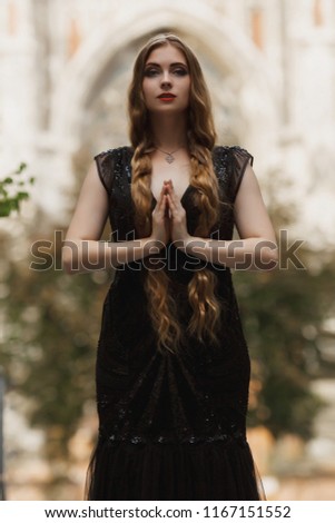 Portrait goth girl outdoor. Wearing black dress, white skin red lips and blonde long hair, standson street .Beautiful witch outdoor. Halloween Vampire beautiful woman portrait