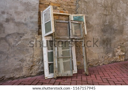 old white window frames with glass backs against a wall