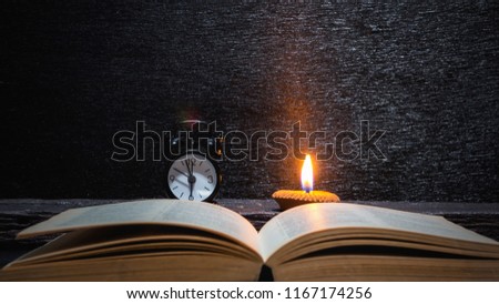 Books and alarm clock with lighting candle on wooden table at night time,Back to School,Education concept,