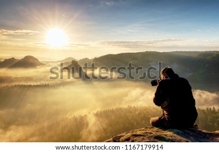 Photographer taking authentic outdoor  photos in autumn landscape  by big dslr camera. Travel photo lifestyle. 
